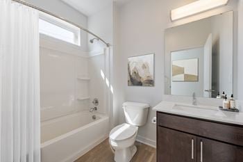 A white toilet sits next to a white bathtub in a bathroom.